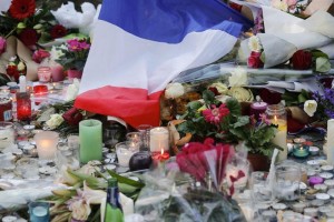 epa05026829 A french flag and flowers are placed at a memorial set near the Bataclan concert venue in Paris, France, 15 November 2015. More than 120 people have been killed in a series of attacks in Paris on 13 November, according to French officials. Eight assailants were killed, seven when they detonated their explosive belts, and one when he was shot by officers, police said. French President Francois Hollande says that the attacks in Paris were an 'act of war' carried out by the Islamic State extremist group.  EPA/JULIEN WARNAND